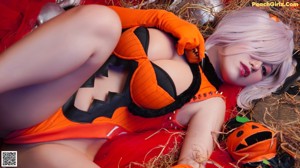 A woman in a halloween costume sitting on a bed with a skeleton.