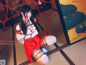 A woman in a red and white outfit is tied up to a net.