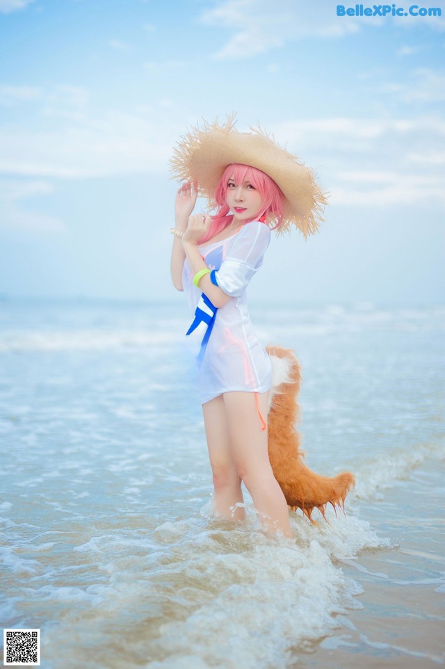 A woman in a straw hat is standing in the water.