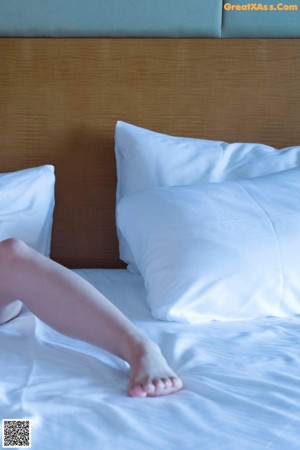 A woman sitting on top of a bed in a white bra.