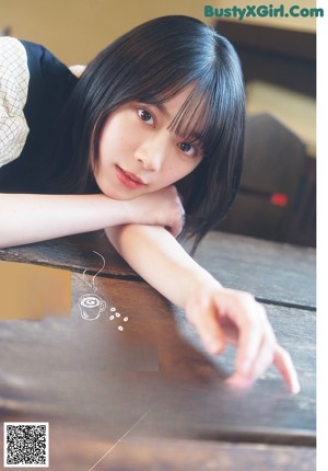 A person laying on a wooden table with their head on the table.