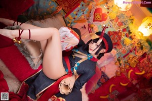 A woman in a black and red outfit sitting on a bed.