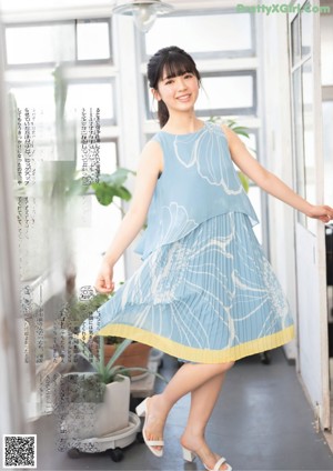 A woman sitting on a wooden bench in a blue dress.