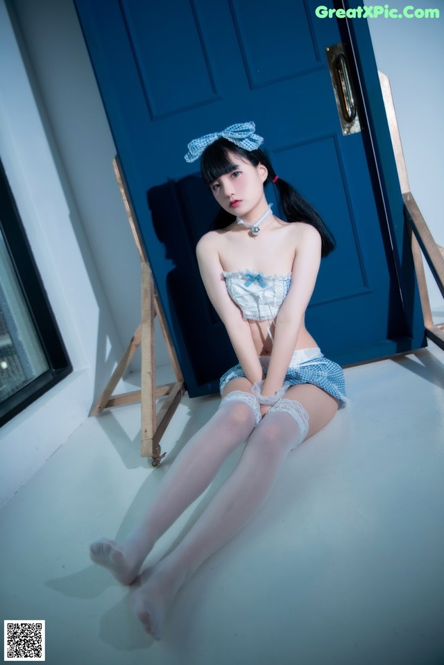 A woman sitting on the floor in front of a blue door.