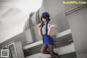 A woman in a blue uniform crouching down on the ground.