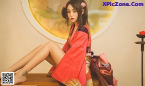 A woman in a pink and black kimono sitting on a chair.
