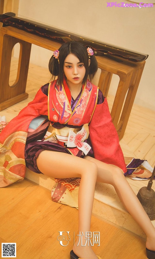 A woman in a kimono sitting on the floor.