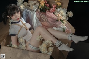 A woman in a white bodysuit is tied up with a rope.