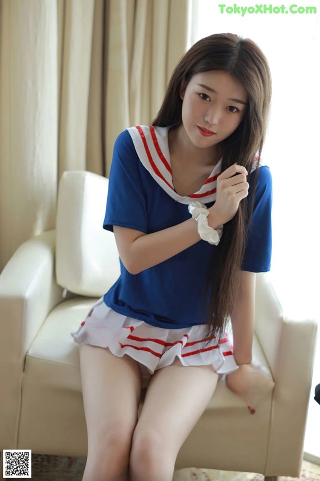 A woman in a sailor outfit sitting on a white chair.