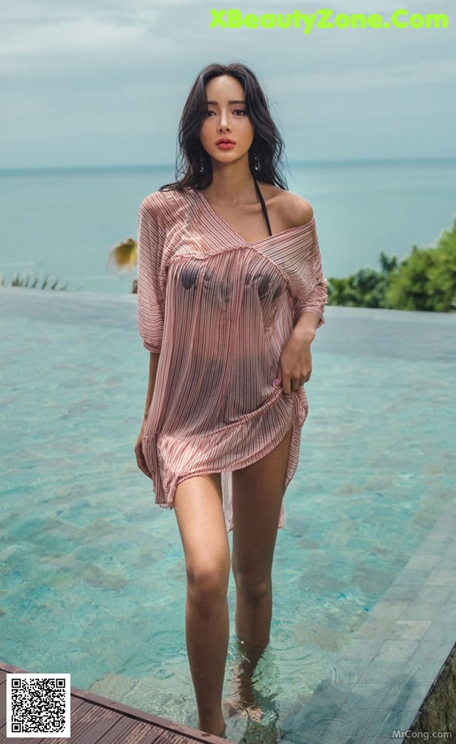 A woman standing in a pool next to the ocean.