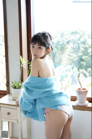 A woman in a blue robe sitting on a kitchen counter.