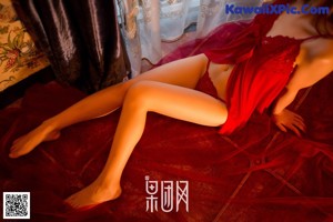 A woman in a red dress sitting on a bed.