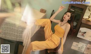 a woman in a yellow top and skirt posing for a picture