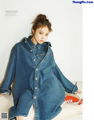 A woman in a white dress sitting on a bed.